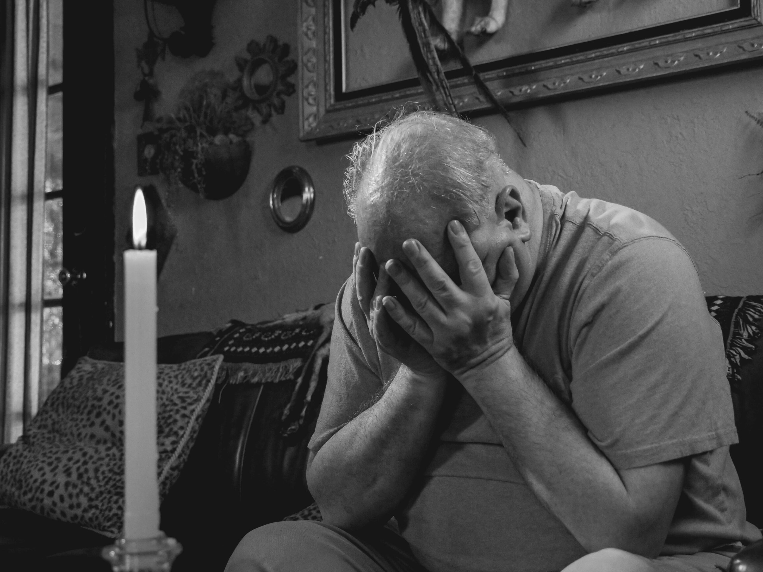 A person crying in front of a candle.